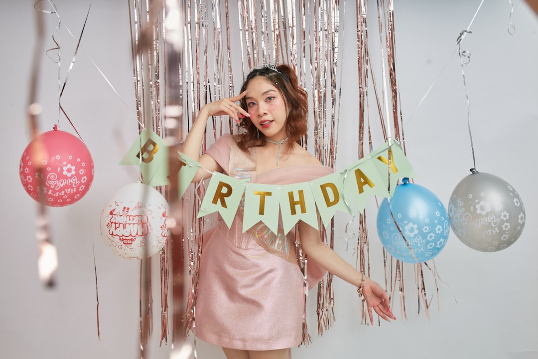A woman in a pink dress holding a happy birthday banner