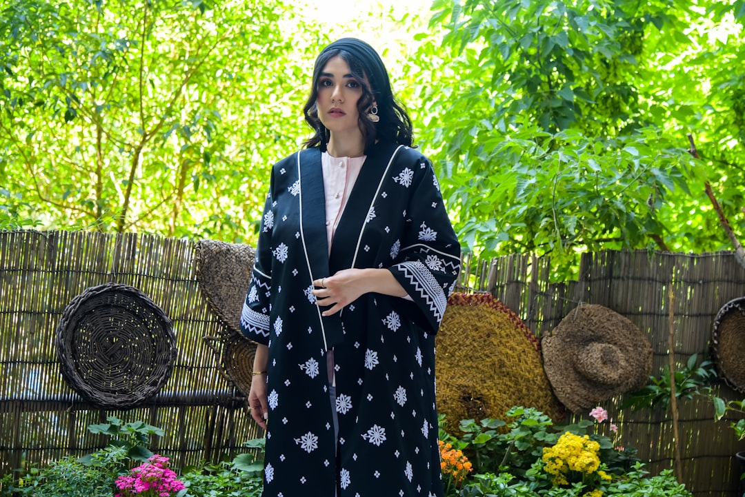 a woman in a black and white kimono standing in a garden