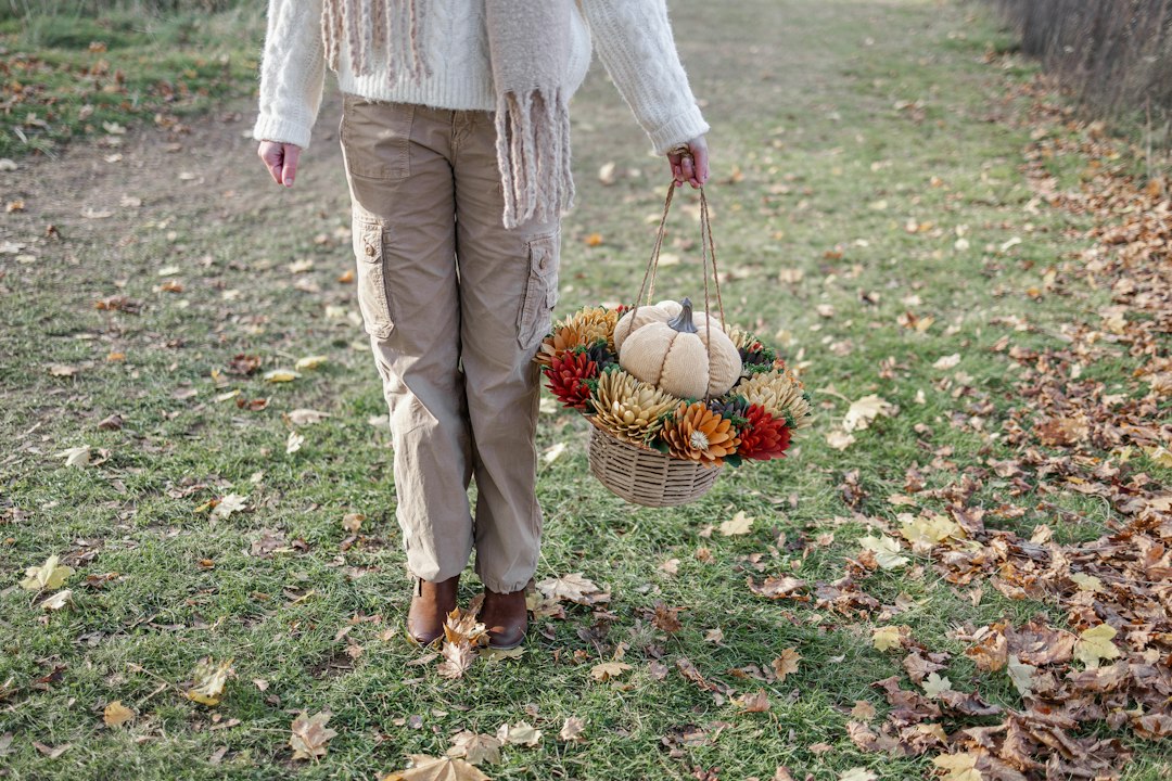 a woman walking down a path carrying a basket of flowers